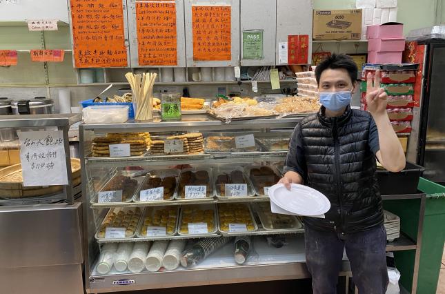 ReThink Disposable business partner poses with new reusable dishware in front of display case of Chinese pastry