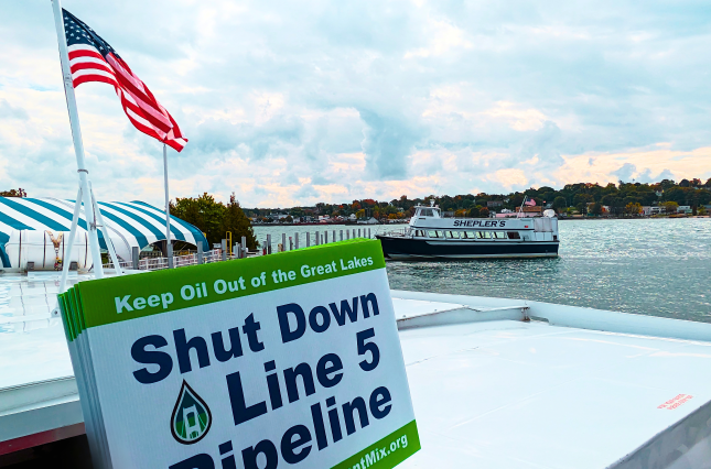 Shut Down Line 5 Pipeline sign held on a boat in the Mackinac Straits between Lake Michigan and Lake Huron