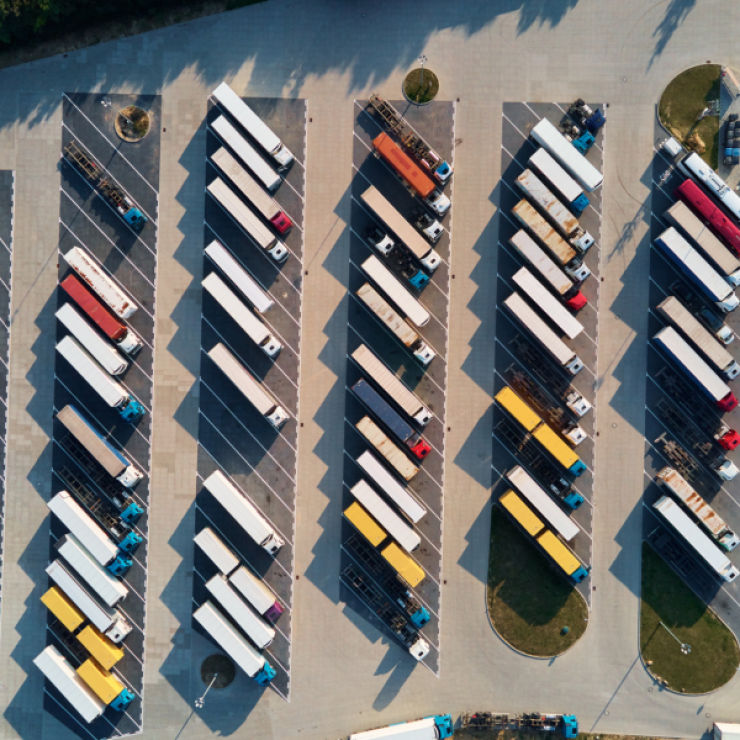 Image of a bunch of trucks in a parking lot by a warehouse - Canva