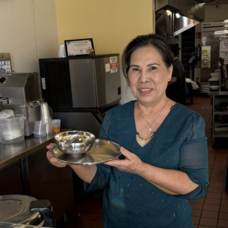Owner of Thai Chili showing off new stainless steel plates and bowls