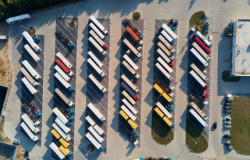 Image of a bunch of trucks in a parking lot by a warehouse - Canva