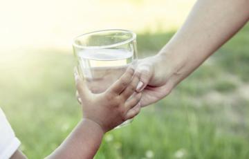 Handing a glass of water to a child. Photo credit: iStock Handing a glass of water to a child. Photo credit: iStock